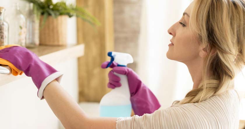 woman dusting mantle with pink gloves on