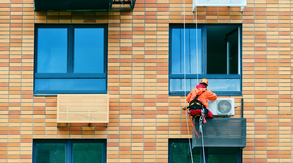 Industrial climber installs air conditioning on the facade of an apartment building