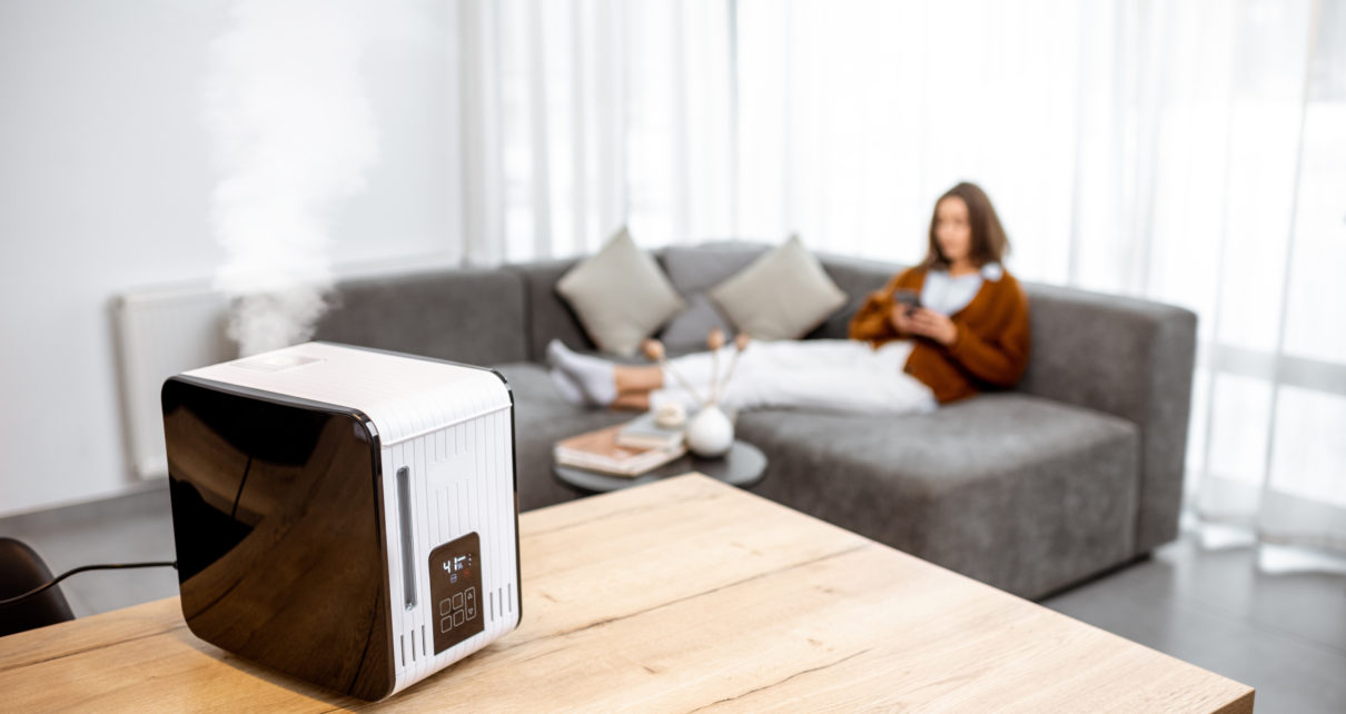woman lounging on couch with humidifier on table in focus