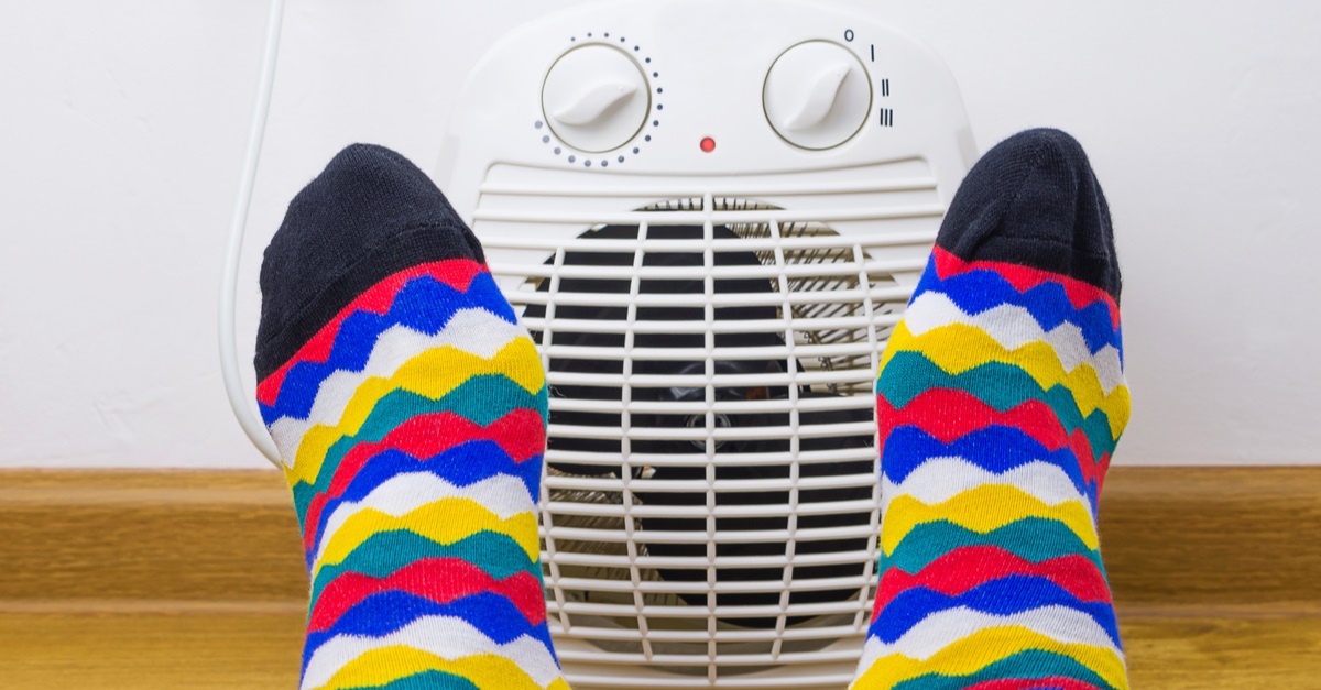 Feet in bright socks near electric heater at home
