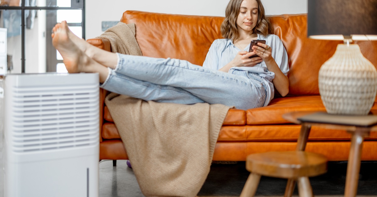 woman sitting on couch with feet up above dehumidifier