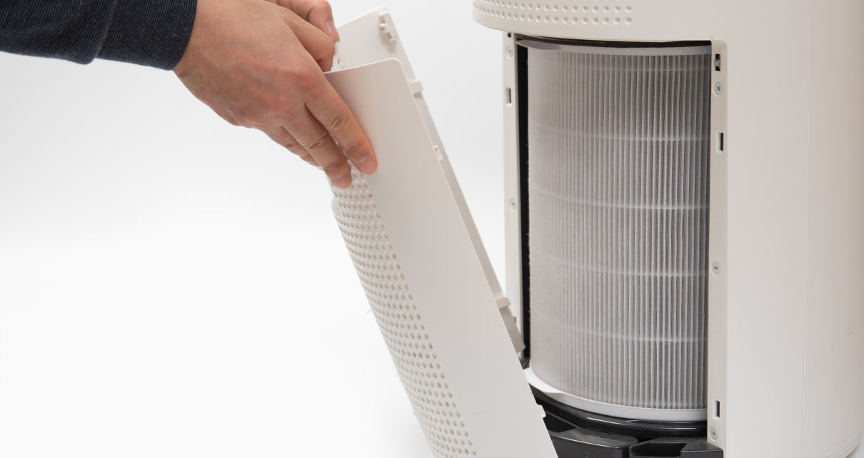 A man's hand changing air purifier filters
