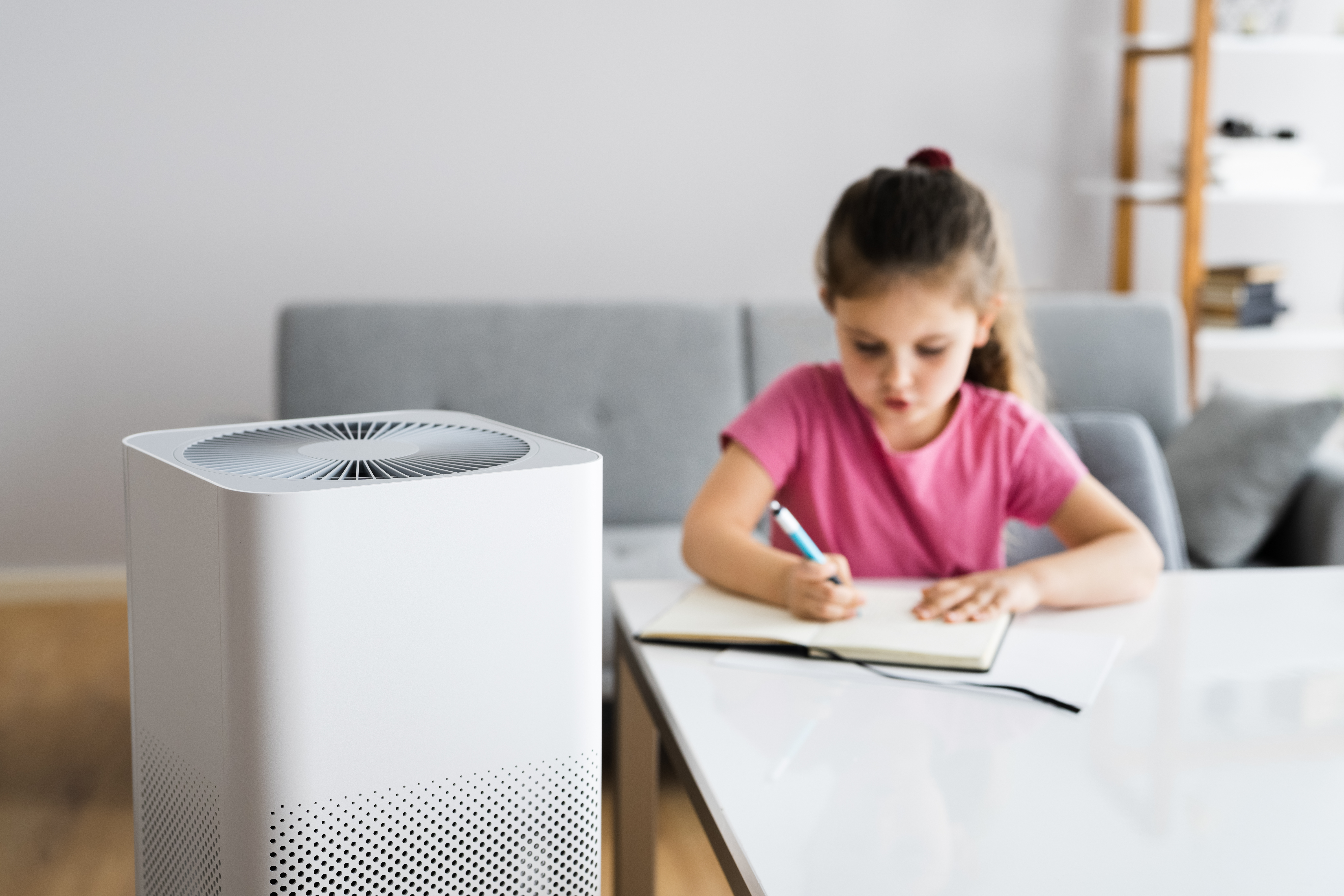 Medify Air Purifier in front of young girl drawing in book at table