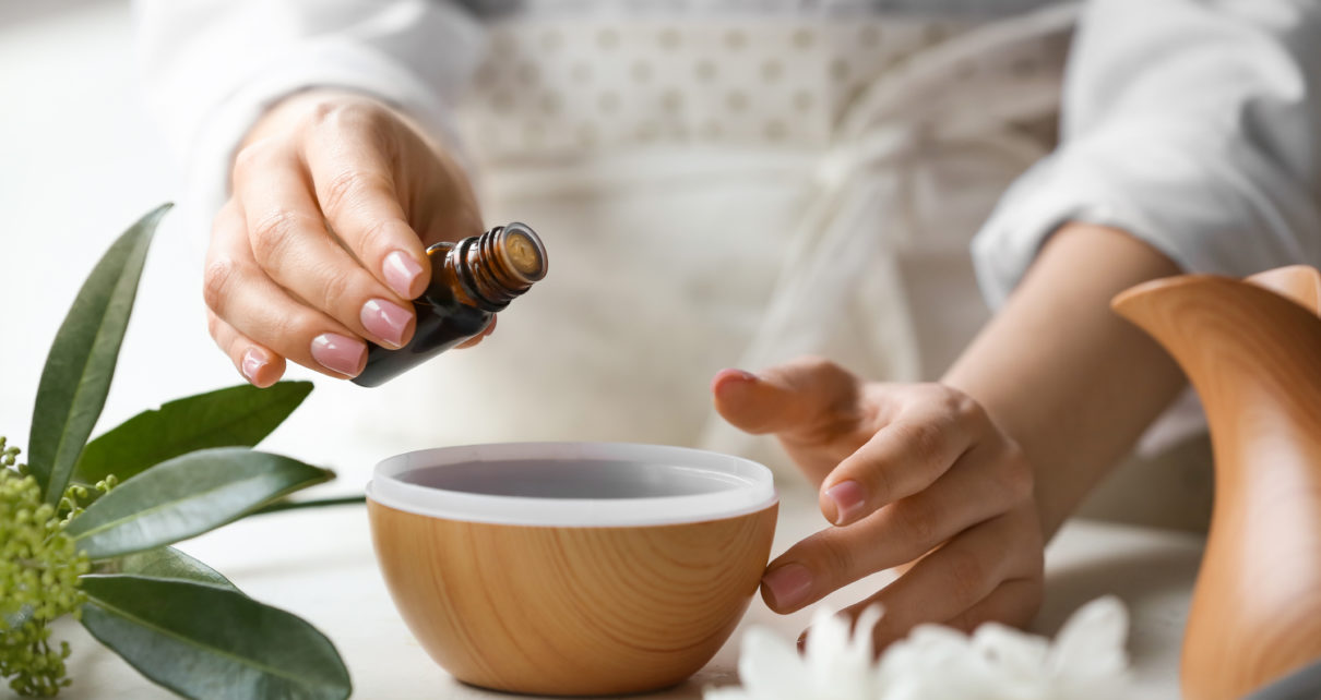 Woman adding essential oil to aroma diffuser