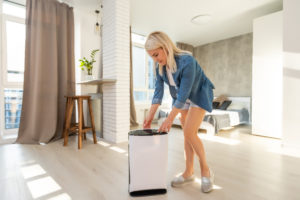 woman standing in room controlling buttons on air purifier