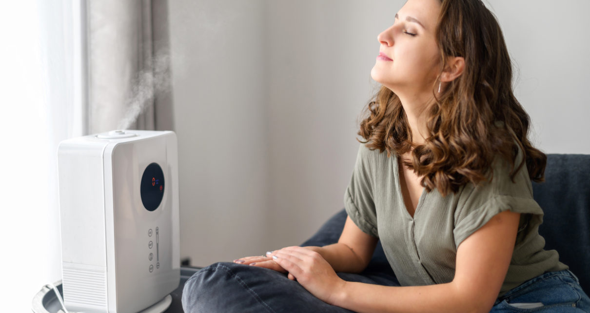 woman taking deep breath next to humidifier