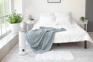 freestanding crane humidifier in stylish bedroom at foot of bed